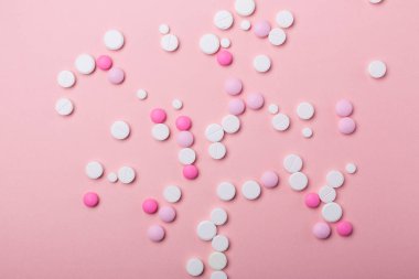 Pembe arka planda pembe ve beyaz haplar. Çeşitli ilaç tabletleri ve haplar yığını. Sağlık hizmetleri.