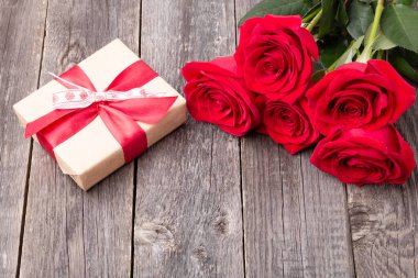 Kırmızı güller ve hediye kutusu gri ahşap masada. Tebrik kartı. Metin için alanı kopyala