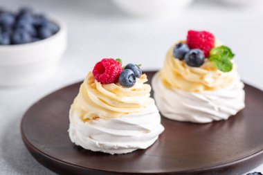 Krem şantili ve ahşap tabakta taze böğürtlenli lezzetli Pavlova pastası. Seçici odak
