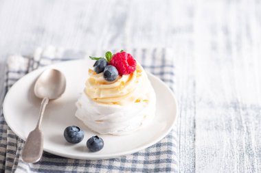 Krem şantili ve beyaz tabakta taze böğürtlenli lezzetli Pavlova pastası. İskandinav tarzı. Yumuşak odak