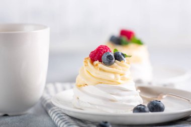 Kahve fincanı ve kremalı Pavlova keki ve beyaz tabakta taze böğürtlen. İskandinav tarzı. Yumuşak odak