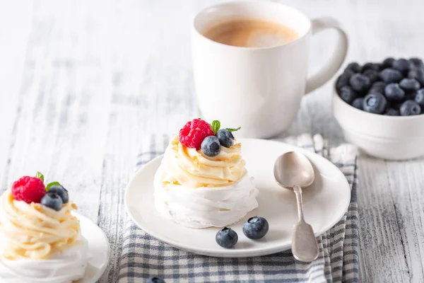 Delicious Pavlova cake with whipped cream and fresh berries. Mug whith coffee. Romantic breakfast