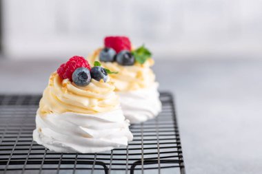 Delicious Pavlova cake with whipped cream and fresh berries on the cooling rack. Selective focus - Image clipart