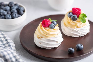 Krem şantili ve ahşap tabakta taze böğürtlenli lezzetli Pavlova pastası. Seçici odak