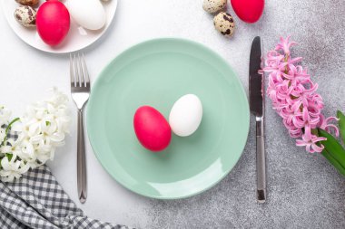 Paskalya sofrası. Yeşil nane tabağı, paskalya yumurtaları, pembe ve beyaz sümbül taştan yapılmış gümüş çatal bıçak takımı. Uzayı kopyala Üst Görünüm - Resim