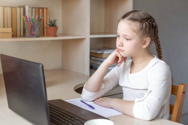 Ciddi bir liseli kız dizüstü bilgisayar ekranına bakıyor. Çevrimiçi eğitim, evde eğitim, evde eğitim, karantina konsepti - Görüntü