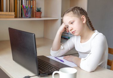 Ciddi bir liseli kız dizüstü bilgisayar ekranına bakıyor. Çevrimiçi eğitim, evde eğitim, evde eğitim, karantina konsepti - Görüntü
