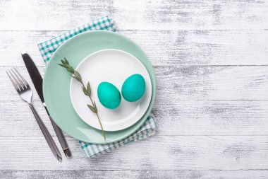 Paskalya yumurtaları ve ahşap arka planda çatal bıçak takımı olan beyaz ve yeşil nane tabağı. Paskalya kompozisyonu. Uzayı kopyala Üst Görünüm - Resim