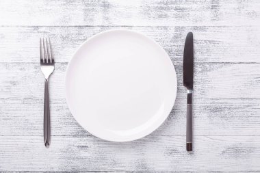 Ahşap arka planda boş beyaz tabak ve çatal bıçak takımı. Uzayı kopyala Üst Görünüm - Resim