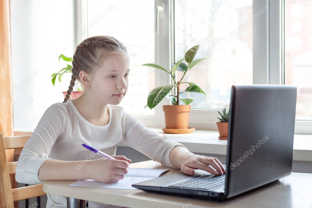 Schoolgirl studying at home using laptop. Home school, online education, home education, quarantine concept - Image