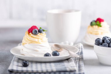 Krem şantili ve taze meyveli lezzetli Pavlova pastası. Bir fincan beyaz kahve. Seçici odak - Resim