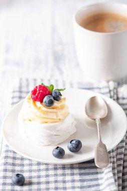 Krem şantili ve taze meyveli lezzetli Pavlova pastası. Bir fincan beyaz kahve. Seçici odak - Resim