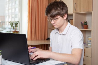 Gözlüklü öğrenci evde dizüstü bilgisayar kullanarak öğreniyor. Ev okulu, çevrimiçi eğitim, ev eğitimi, karantina konsepti - Görüntü