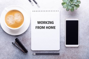 Bir fincan kahvesi, not defteri, akıllı telefonu ve malzemeleri olan ev işyeri. Ev konsepti üzerinde çalışıyorum. Üst Görünüm - Resim