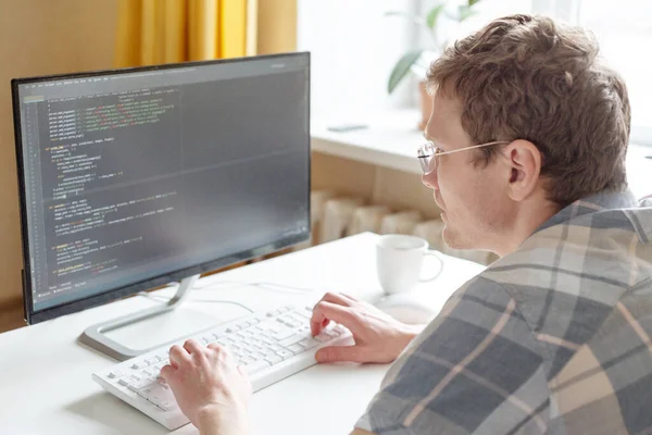 Programcı evden, uzaktan kumandalı, ev ofisinden çalışıyor. Gözlüklü bir adam monitöre bakıyor. Uzak çalışma konsepti - Resim