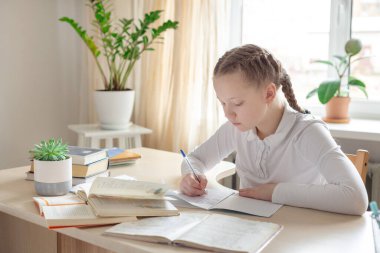Liseli kız evde ders çalışıyor. Uzaktan eğitim, evde eğitim. Kişisel izolasyon kavramı - Resim