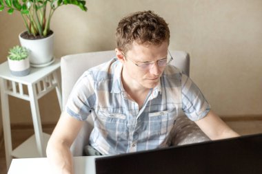 Programcı evden, uzaktan kumandalı, ev ofisinden çalışıyor. Gözlüklü bir adam monitöre bakıyor. Uzak çalışma konsepti - Resim