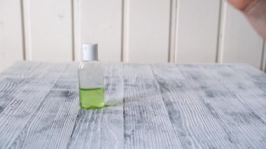 Kadın eli masadan dezenfektan jöleli bir şişe alır. Temiz eller için Coronavirus el dezenfektanı jeli. Antiseptik, hijyen ve sağlık sigortası konsepti. 4k görüntü.