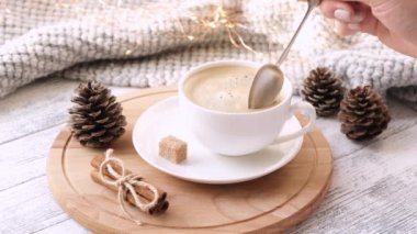 Kadın eli kahveyi karıştırır. Kahve fincanı, kazak, tarçın, esmer şeker. Sıcak sonbahar kompozisyonu. Hygge konsepti. 4K görüntü