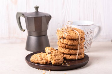 Bir fincan kahve, bir yığın yulaflı kurabiye, beyaz ahşap arka planda kahve makinesi ev yapımı fırın sağlıklı yiyecek konsepti.