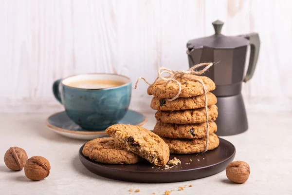 Cup of coffee, stack of oatmeal cookies, coffee maker on white wooden background Homemade bakery Healthy food snack concept