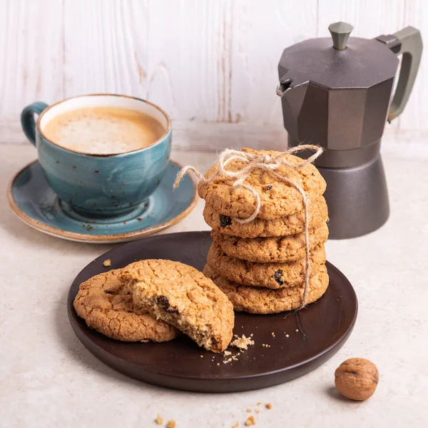 Cup of coffee, stack of oatmeal cookies, coffee maker on white wooden background Homemade bakery Healthy food snack concept