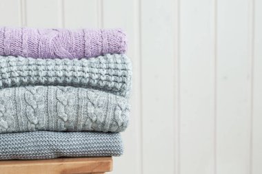 Ahşap bir merdivende bir yığın rahat örgü kıyafet. İskandinav tarzı. Beyaz ahşap duvar