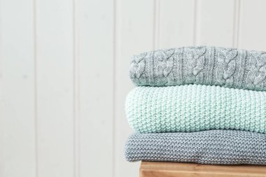 Ahşap bir merdivende bir yığın rahat örgü kıyafet. İskandinav tarzı. Beyaz ahşap duvar