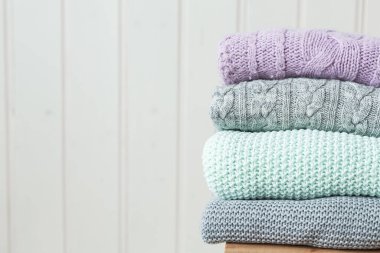 Ahşap bir merdivende örülmüş bir kazak yığını. İskandinav tarzı. Beyaz ahşap duvar