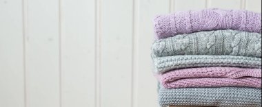 Ahşap bir merdivende bir yığın rahat örgü kıyafet. Web pankartı İskandinav tarzı. Beyaz ahşap duvar