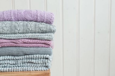 Ahşap bir merdivende örülmüş bir kazak yığını. İskandinav tarzı. Beyaz ahşap duvar