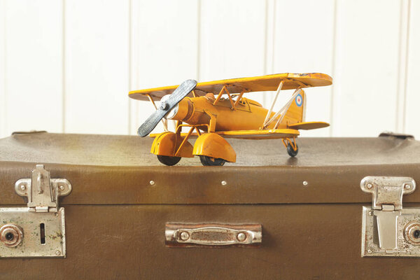 Toy yellow metal plane Old retro suitcases White wooden background Vintage tinting Copy space