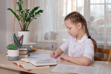 Schoolgirl studying at home. Distance education, home education. Self isolation concept - Image clipart