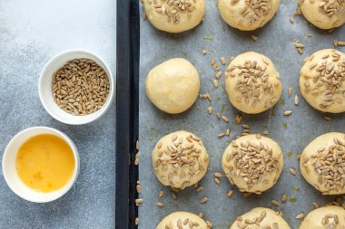 Tavaya tohum serpiştirilmiş çiğ hamur topları. Ev yapımı çörekler. Üst Görünüm - Resim