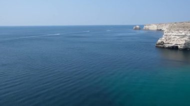 Güneşli bir günde mavi denizin kayalık sahilinin güzel manzarası. 4k video