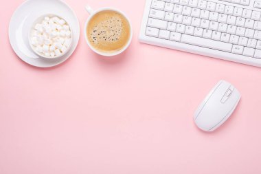 Pembe arka planda bir fincan kahve, klavye ve bilgisayar faresi olan bir kadın işyeri. Üst Görünüm - Resim