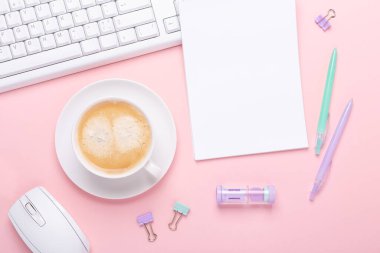 Pembe arka planda bir fincan kahve ve pastel renkli kırtasiye aksesuarları olan kadın işyeri. Üst Görünüm - Resim
