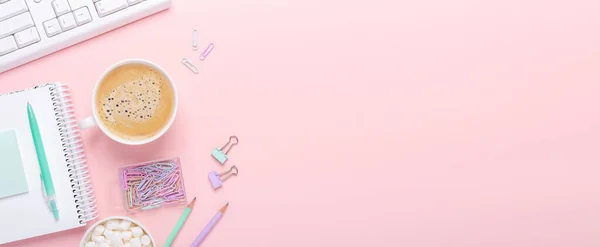 Pembe arka planda bir fincan kahve ve pastel renkli kırtasiye aksesuarları olan kadın işyeri. Yatay Pankart - Resim