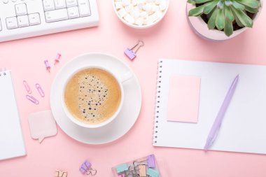 Pembe arka planda bir fincan kahve ve pastel renkli kırtasiye aksesuarları olan kadın işyeri. Üst Görünüm - Resim