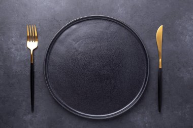 Karanlık masa ayarı. Metnin için boş seramik tabak ve çatal bıçak takımı kopyalama alanı - Resim