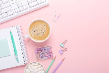 Şık bir iş yeri, blog yazarı ya da tasarımcı ofisi. Pembe arka planda bir fincan kahve ve kırtasiye malzemesi. Düz konum - Resim