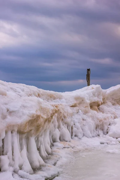Costa helada congelada en un día nublado con un pilar Jetty en un Ph — Foto de Stock