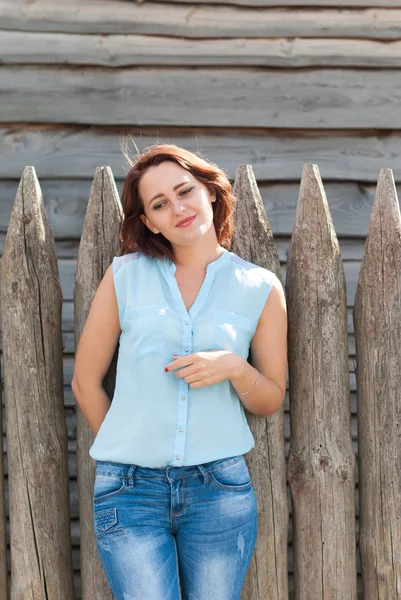 Young beautiful girl on the background of a wooden fence. — Stock Photo, Image