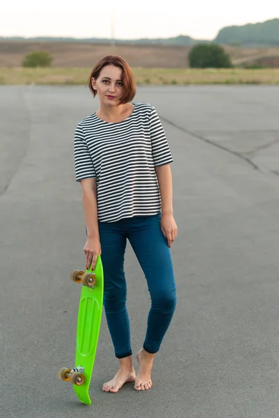 Girl standing barefoot on the asphalt with a skateboard. — Stock Photo, Image