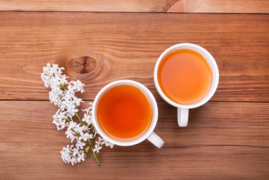 İki fincan çay ve bir ahşap zemin üzerine Eflatun bir bud.