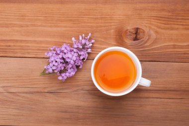 Ahşap arka plan üzerinde çay ve eflatun çiçek fincan.