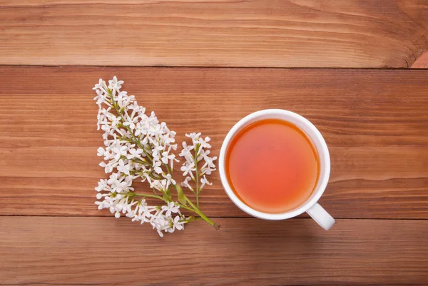 一杯の紅茶と木製の背景にライラックの花束. — ストック写真