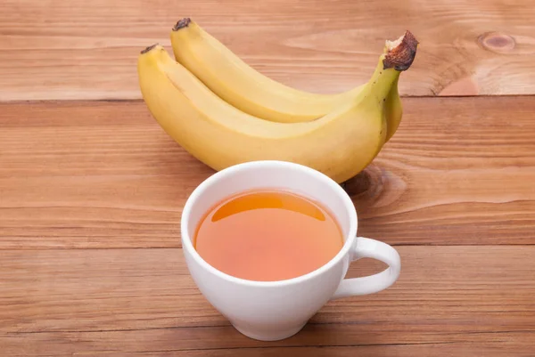 Tasse Tee und Bananen auf einem hölzernen Hintergrund. — Stockfoto