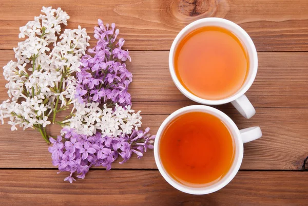 两杯茶和紫丁香花上一个木制的背景. — 图库照片