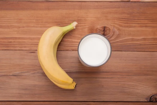 Glass of milk and bananas on a wooden background. View from above . — Stock Photo, Image